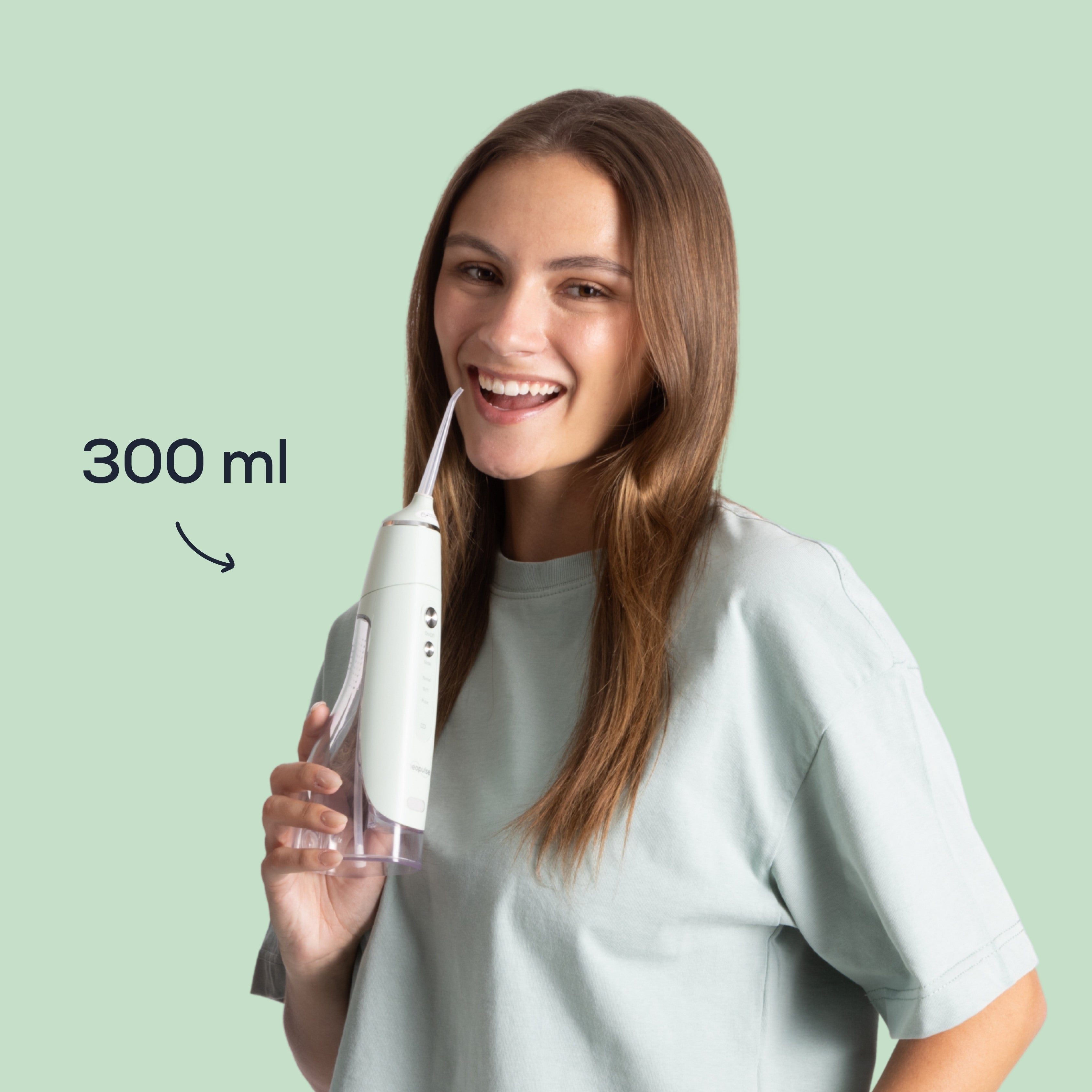 Femme utilisant le jet dentaire MY FIRST NEOPULSE vert avec son réservoir de 300 ml pour le nettoyage interdentaire