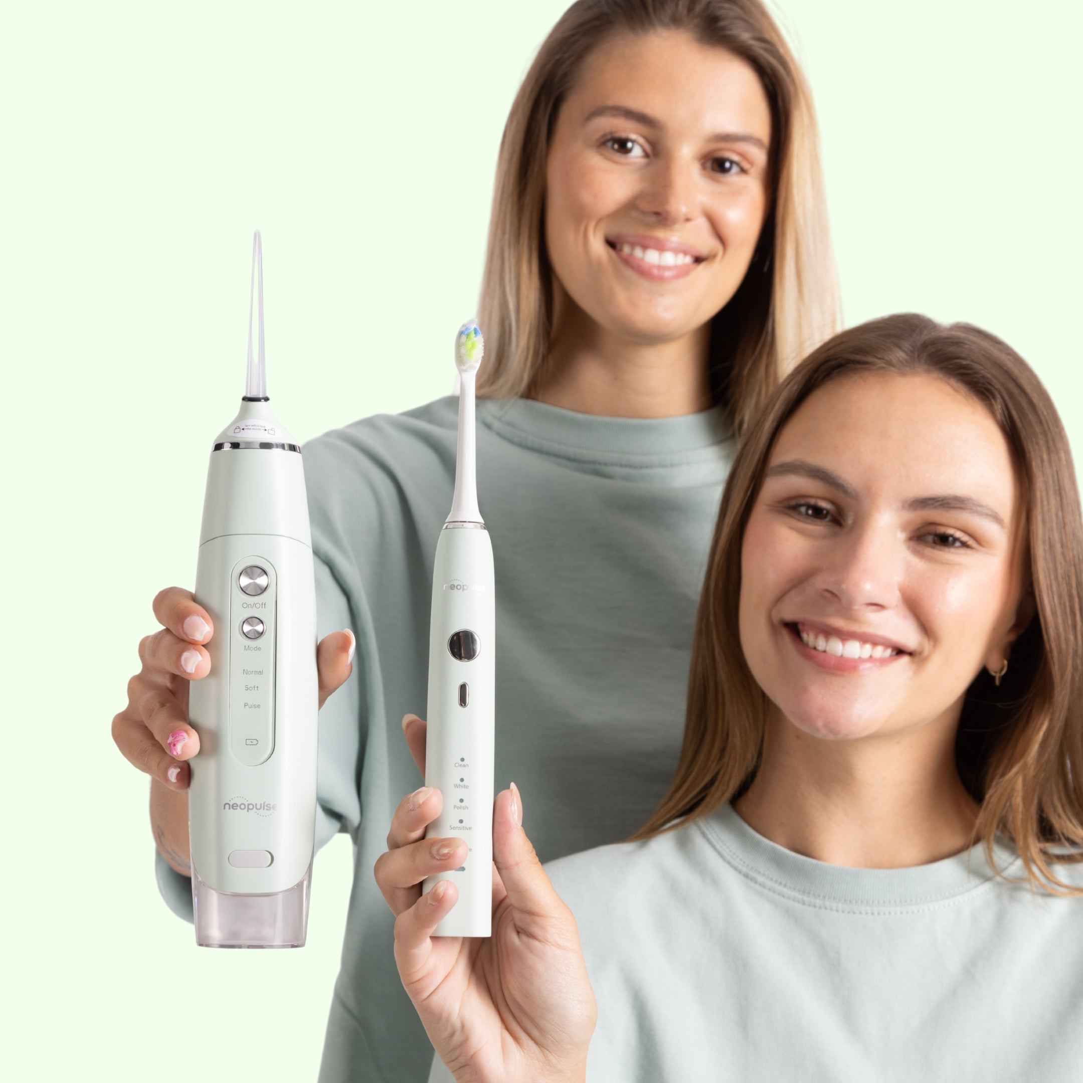 Deux femmes souriantes montrant une brosse à dents NEOSONIC verte et un jet dentaire MY FIRST vert