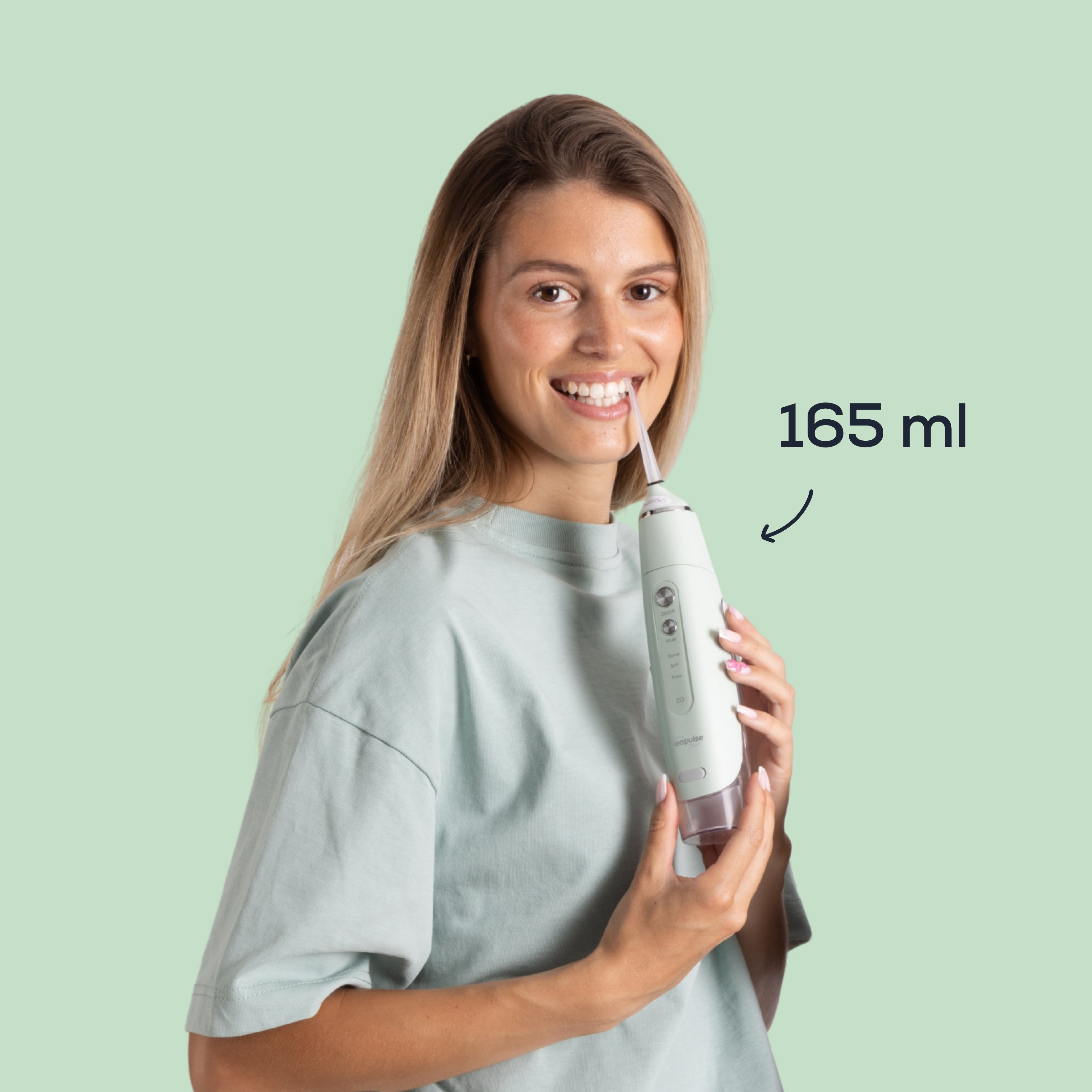 Femme utilisant le jet dentaire MY FIRST NEOPULSE vert avec son réservoir de 165 ml pour le nettoyage interdentaire